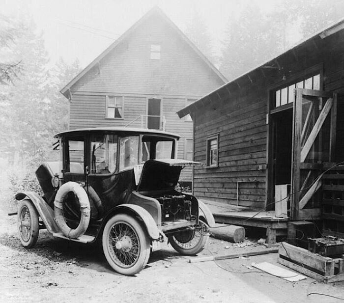 Coche antiguo estacionado frente a una casa de madera, evocando días pasados históricos.