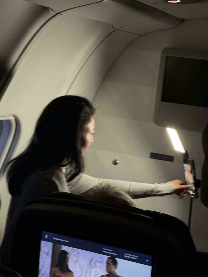 Influencer tomando una selfie en el avión, sin preocuparse por las molestias.