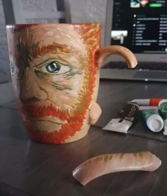 Taza con cara pintada y extraña oreja en la mesa, representando una imagen aleatoria y absurda.