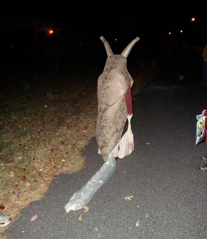 Persona en disfraz de babosa caminando por la calle de noche, una imagen aleatoria y rara.