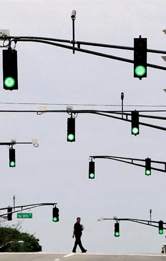 Semáforos en verde, múltiples niveles, persona cruzando; imagen aleatoria y absurda.