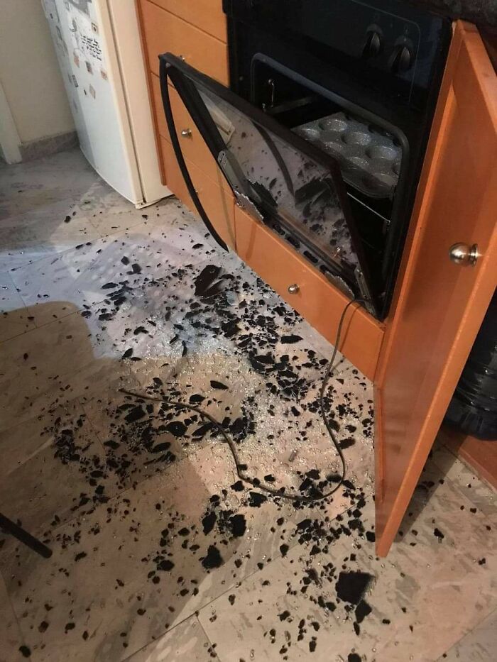 Puerta de horno rota con vidrio esparcido en el suelo, destacando accidente costoso en la cocina.