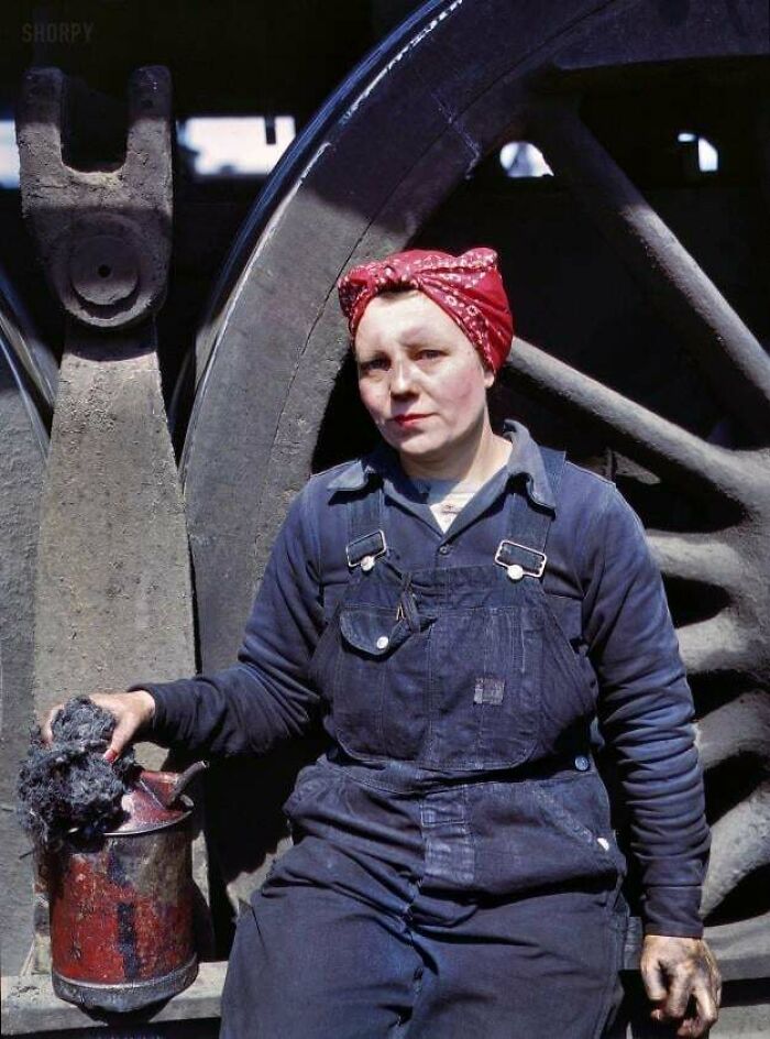 Mujer trabajadora con pañuelo rojo junto a maquinaria industrial en foto histórica fascinante sobre trabajos del pasado.