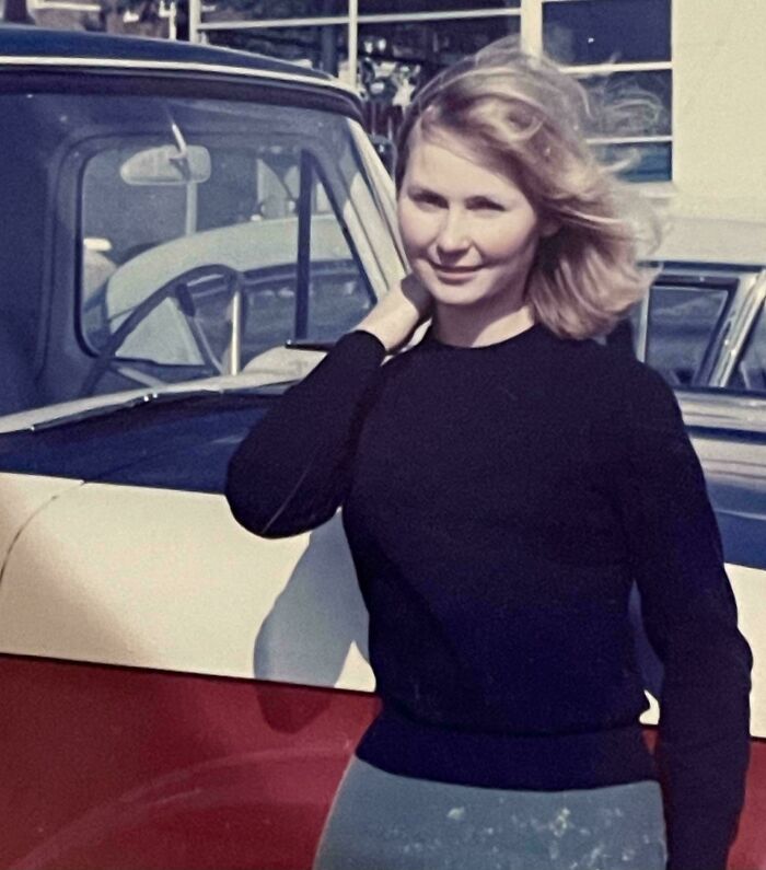 Mujer posando junto a un automóvil antiguo en una foto histórica fascinante que va más allá de los libros de texto.