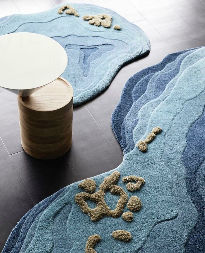 Alfombra azul con diseño de geografía, junto a mesa redonda blanca, ejemplifica diseños poco prácticos en la realidad.