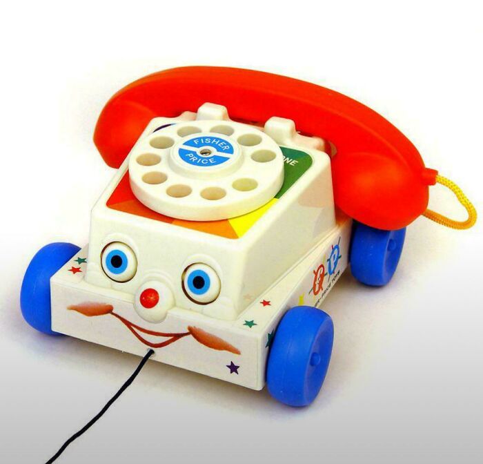Teléfono de juguete Fisher Price antiguo con ruedas y disco giratorio, recuerdo nostálgico de la juventud y el pasado.