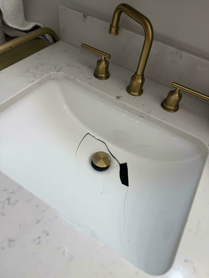 Lavabo de mármol con grieta grande junto al grifo dorado, muestra de fallos caros.