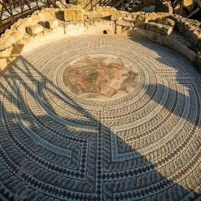Mosaico antiguo impresionante, diseño detallado rodeado de piedras, ejemplo de creaciones humanas sorprendentes.
