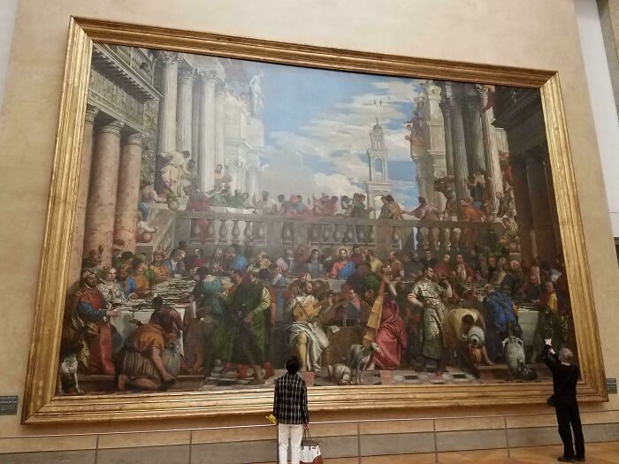 Visitantes admirando una pintura monumental en el museo, mostrando perspectivas de lugares conocidos.