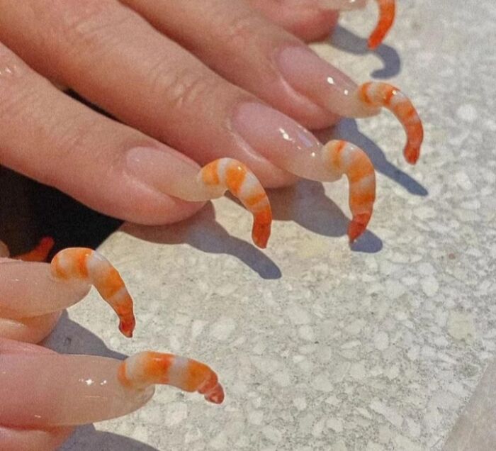 Uñas decoradas con camarones realistas, generando una sensación incómoda.