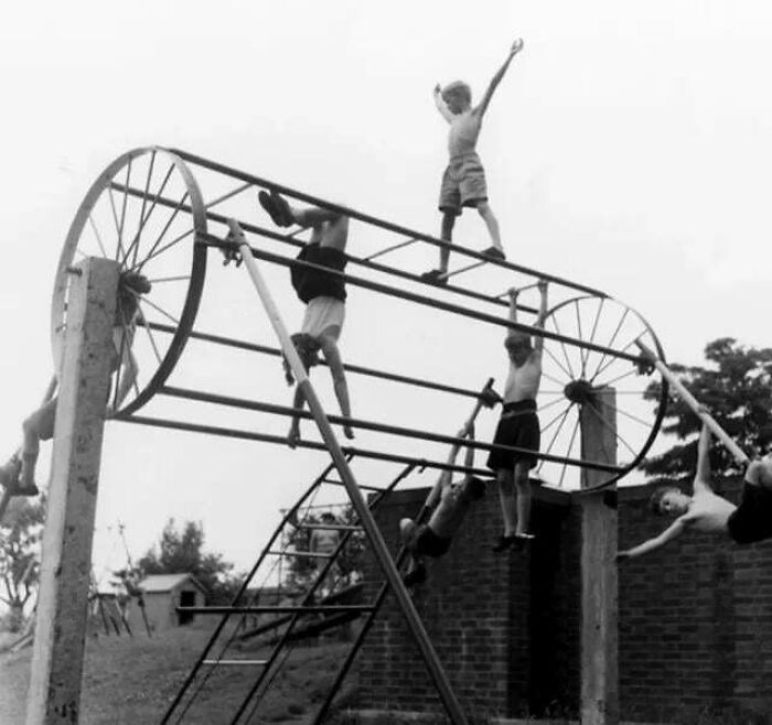 Niños jugando en estructura metálica antigua en una foto histórica fascinante en blanco y negro.