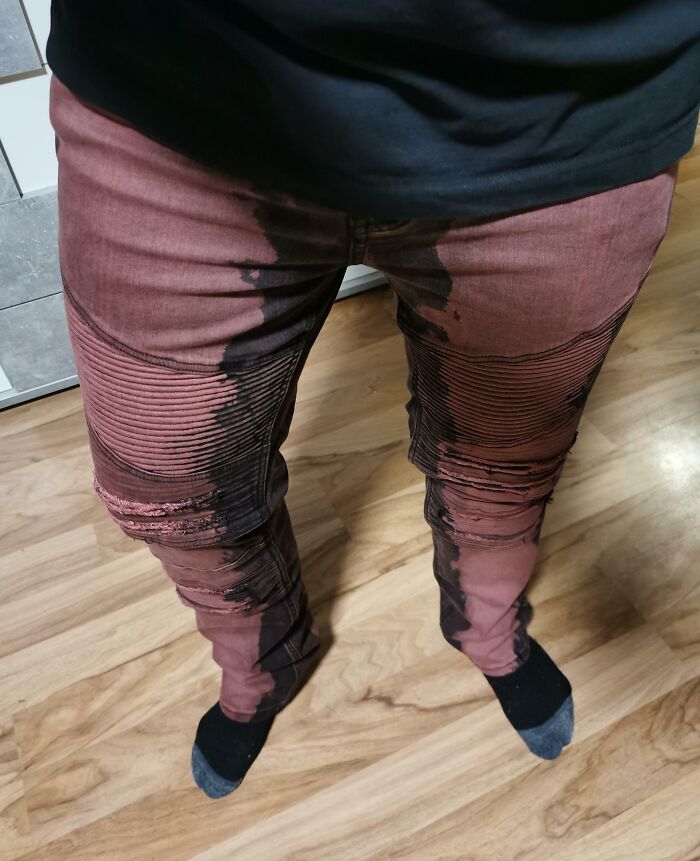 Pantalones con diseño manchado en el suelo de madera clara, mostrando un ejemplo de diseño fallido.
