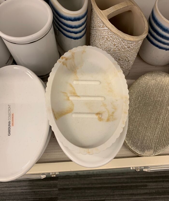 Jabonera ovalada con manchas, rodeada de recipientes decorativos, un ejemplo de diseño que no funcionó en la realidad.
