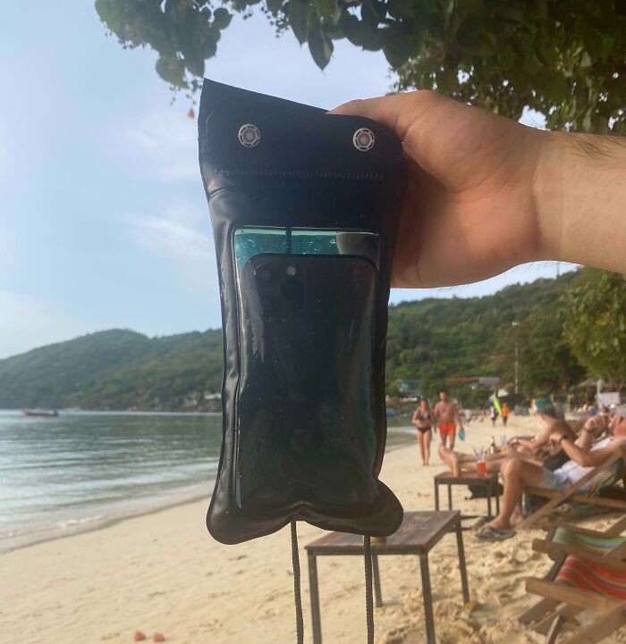 Teléfono mojado en funda impermeable junto al mar, ejemplo de accidente costoso en la playa.