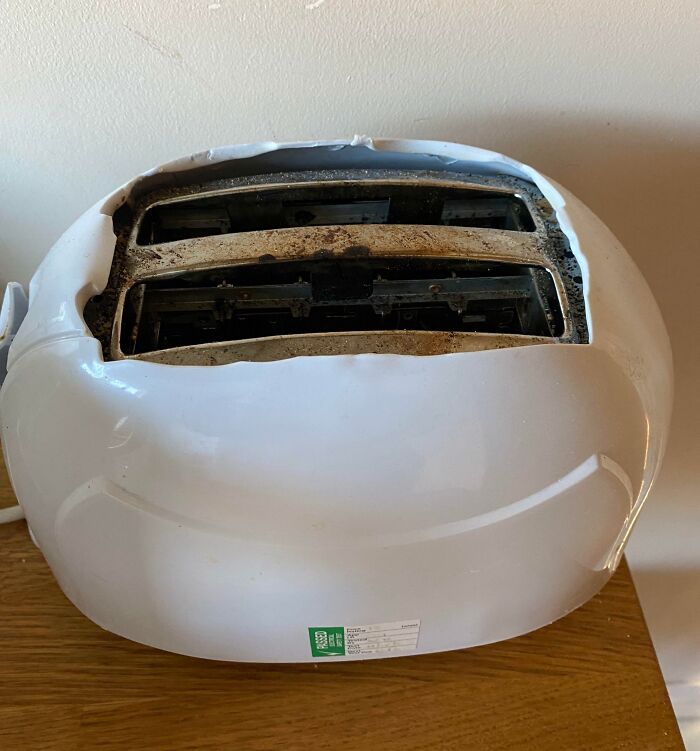 Tostadora rota y derretida, diseño fallido en la realidad sobre una mesa de madera.