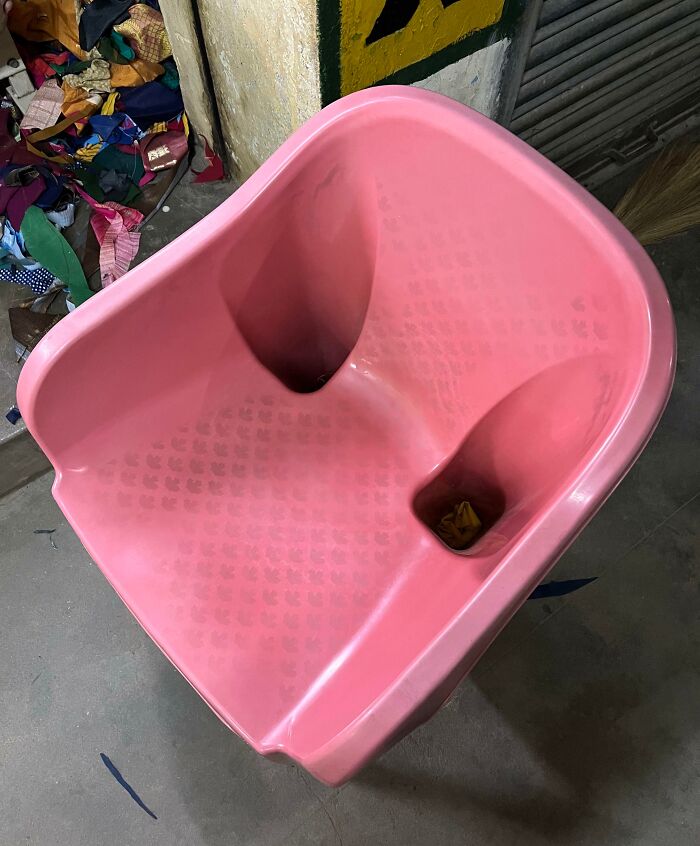 Silla rosa de diseño inusual con dos cavidades, ubicada en un entorno industrial.