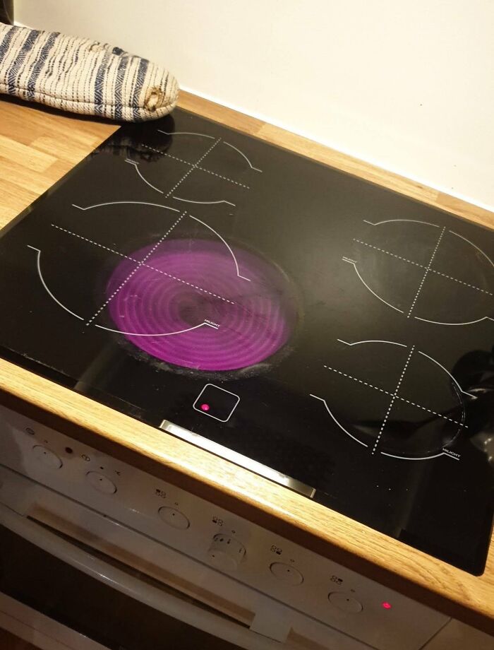 Estufa eléctrica con un diseño poco práctico, la hornilla encendida en color púrpura no calienta la cazuela a la derecha.