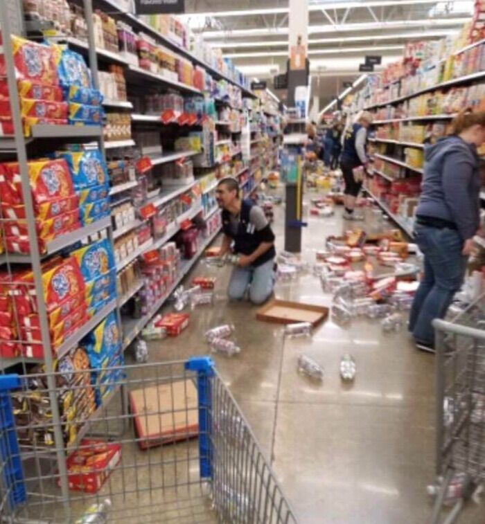 Empleado recogiendo productos en pasillo desordenado en supermercado, relacionado con clientes ignorantes y frustrantes.