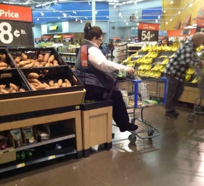 Empleado en supermercado usando carrito motorizado cerca de productos frescos, ilustrando experiencias con clientes frustrantes.