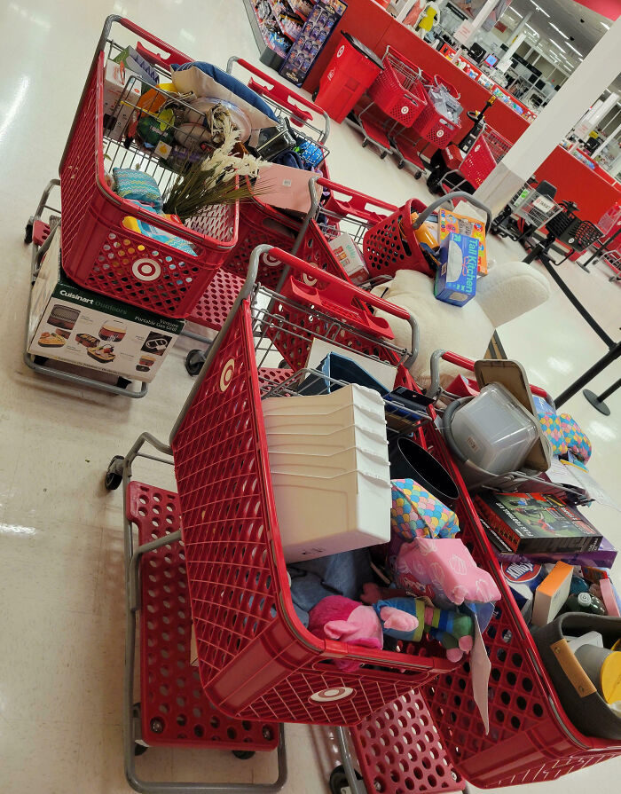 Carritos de compras llenos de productos variados en tienda, ilustrando historias de clientes frustrantes y empleados.