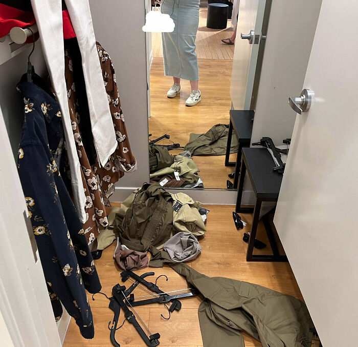 Probador de ropa desordenado con varias prendas tiradas y colgadas, mostrando experiencia de empleados con clientes frustrantes.
