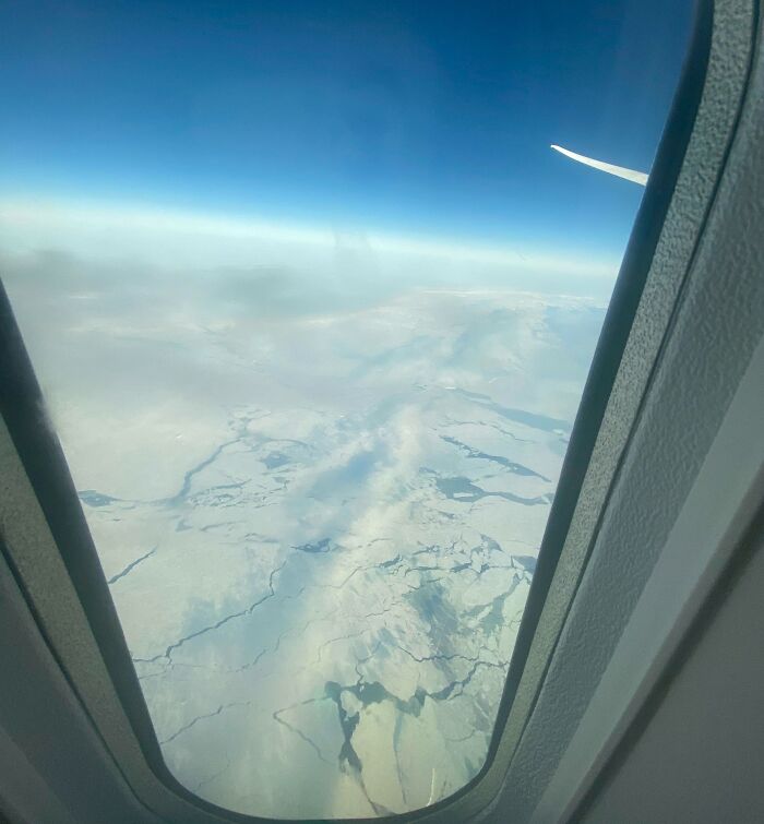 Vista aérea de paisaje nevado desde la ventana del avión, mostrando perspectivas de lugares conocidos.