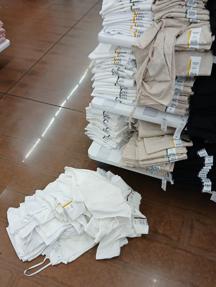 Montones de ropa doblada y apilada en tienda, reflejando contexto de empleados contando historias de clientes frustrantes.