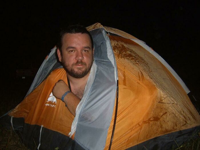 "Hombre en una pequeña tienda de campaña naranja durante la noche, un posible error digno de compartirse en internet."