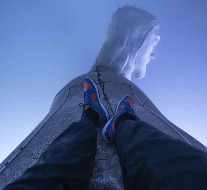 Persona apoyada en la base del Cristo Redentor, con vista hacia la estatua, ofreciendo una perspectiva distinta.