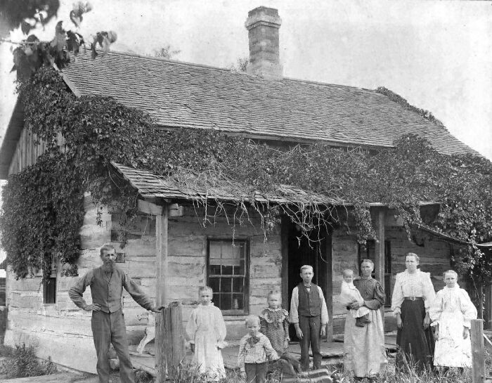 Familia histórica frente a una casa cubierta de enredaderas, imagen en blanco y negro de fotos históricas fascinantes.