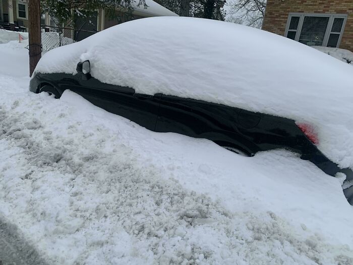 Coche cubierto de nieve tras una fuerte tormenta, mostrando un día laboral complicado.