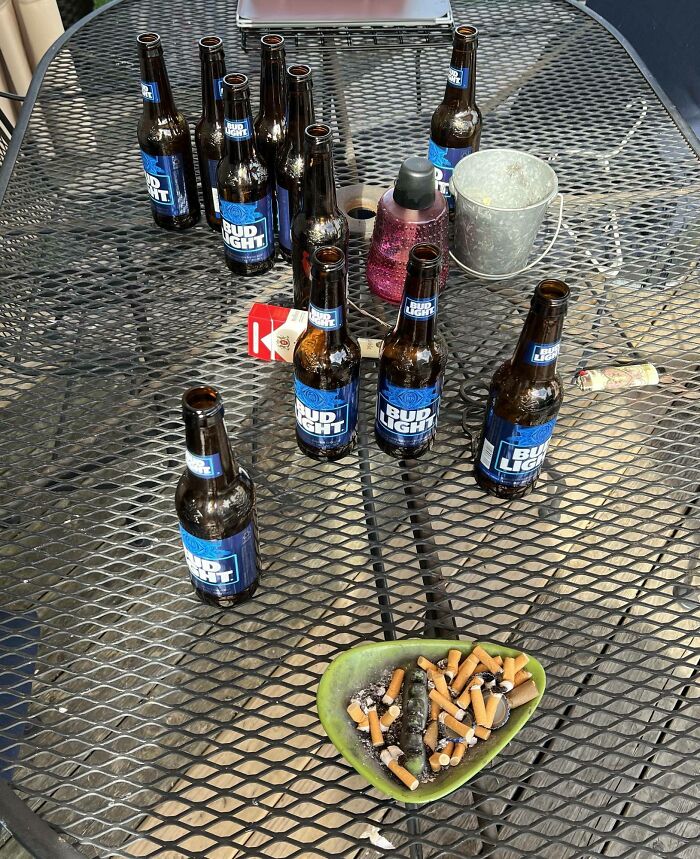 Botellas vacías y colillas de cigarro en una mesa, reflejando una reunión familiar difícil.