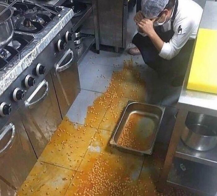 Persona en una cocina con comida derramada en el suelo, reflejando un día difícil en el trabajo.