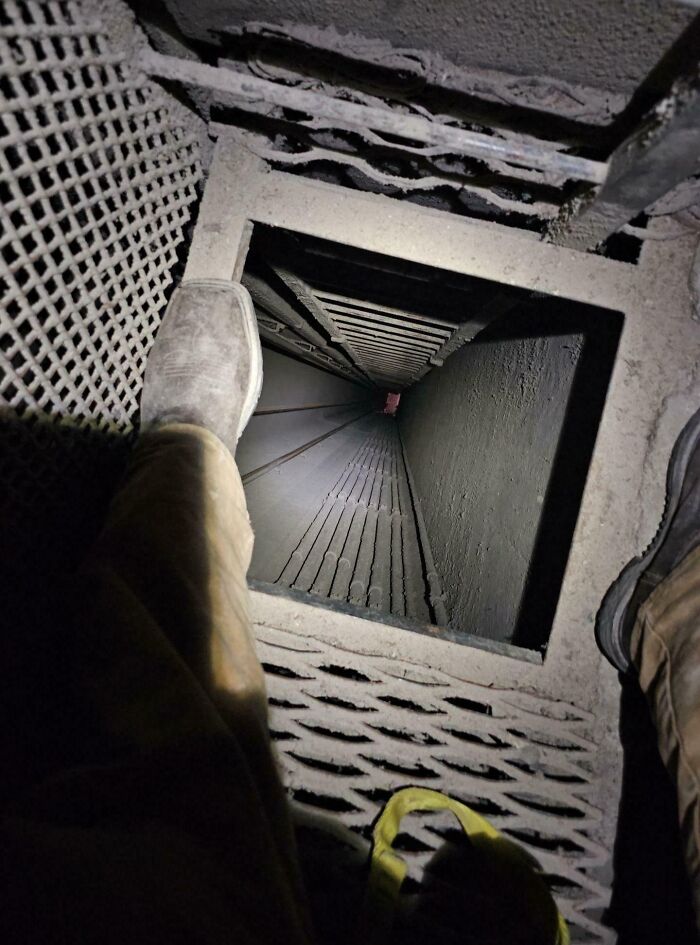 Trabajador frente a un pozo profundo en una estructura de metal, ilustrando un día difícil en el trabajo.