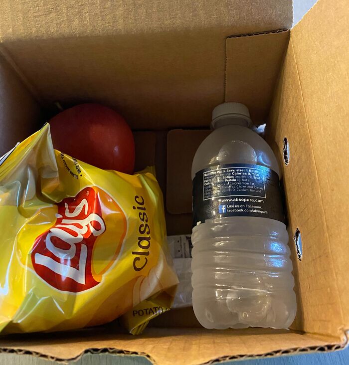 Caja de almuerzo con papas fritas, manzana y agua, mostrando un día laboral desafortunado.