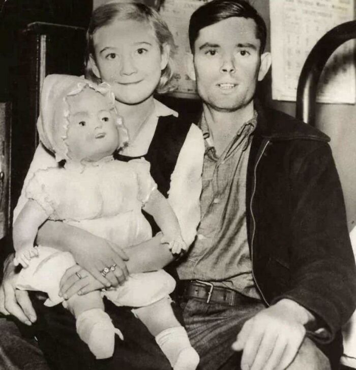 Pareja vintage con muñeca en un entorno inquietante del pasado.