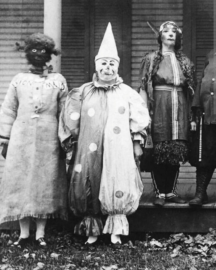 Personas disfrazadas con atuendos inquietantes en una fotografía antigua en blanco y negro.