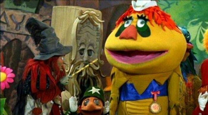 Personajes coloridos de un antiguo programa infantil, con disfraces y fondo de bosque, evocan sensación inquietante.