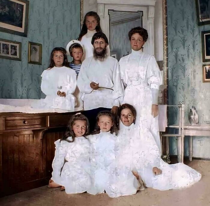 Grupo de personas en imagen antigua con ropa blanca, ambiente inquietante y expresión seria.