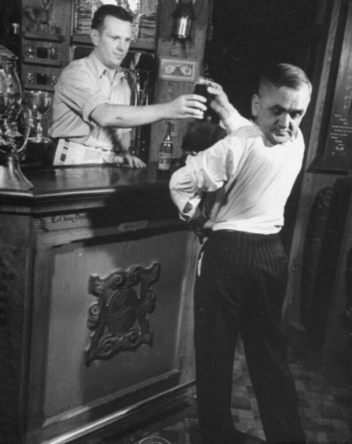 Un barman sirviendo una bebida en un bar antiguo, escena inquietante del pasado.
