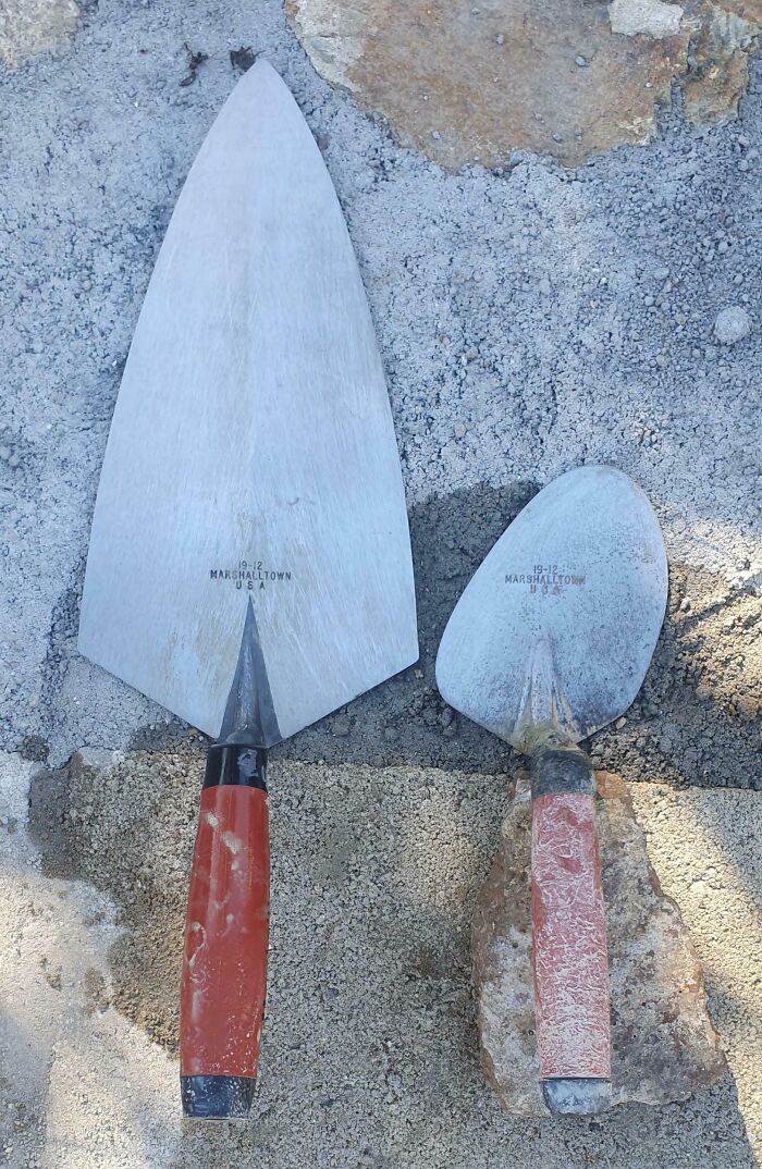 Dos paletas de albañil desgastadas por el tiempo, sobre una superficie de concreto.