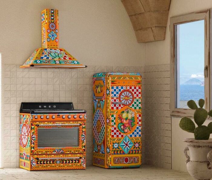 Cocina poco práctica con electrodomésticos de diseño colorido junto a una ventana con vista al mar.