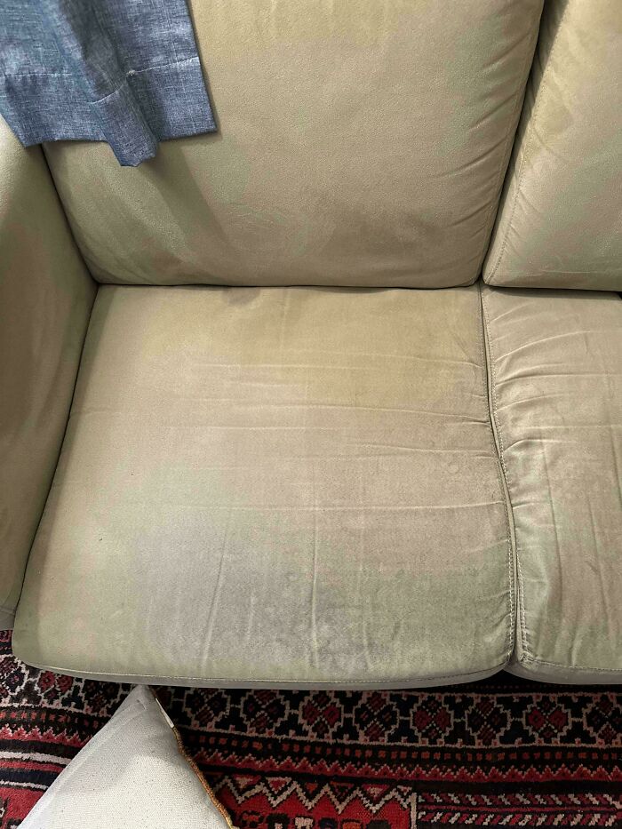 Sofá desgastado y cojín en alfombra, ejemplo de tendencias de interiorismo poco prácticas.