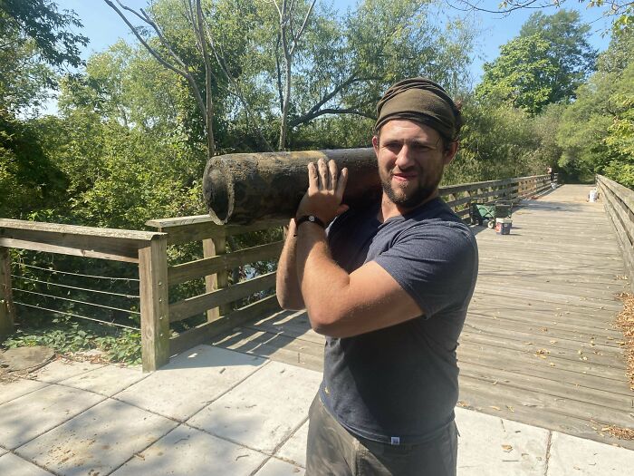 Un hombre en un puente, levantando un objeto peligroso similar a un proyectil, sonriente y con bandana.