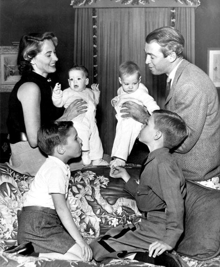 Familia en una escena histórica, con dos adultos sonriendo a cuatro niños en un ambiente hogareño.