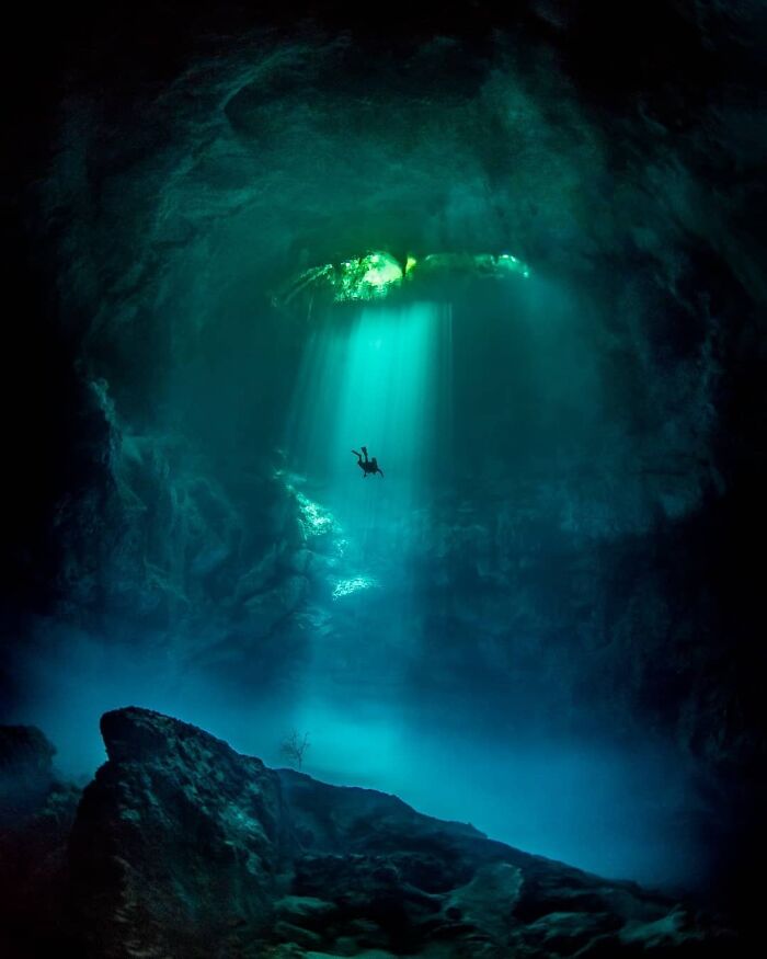 Persona buceando en una cueva subterránea iluminada, mostrando una perspectiva distinta de lugares conocidos.