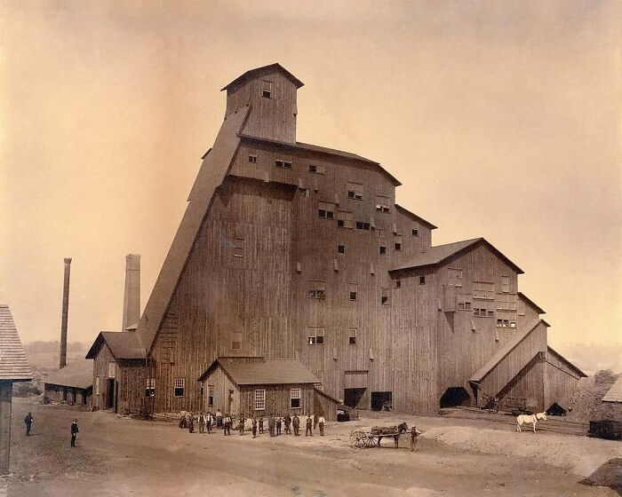 Antigua estructura industrial con personas y caballo, evocando el pasado histórico.