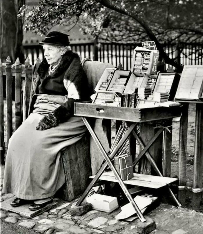 Vendedora de libros antiguos en la calle, retrato histórico que evoca la nostalgia del pasado.