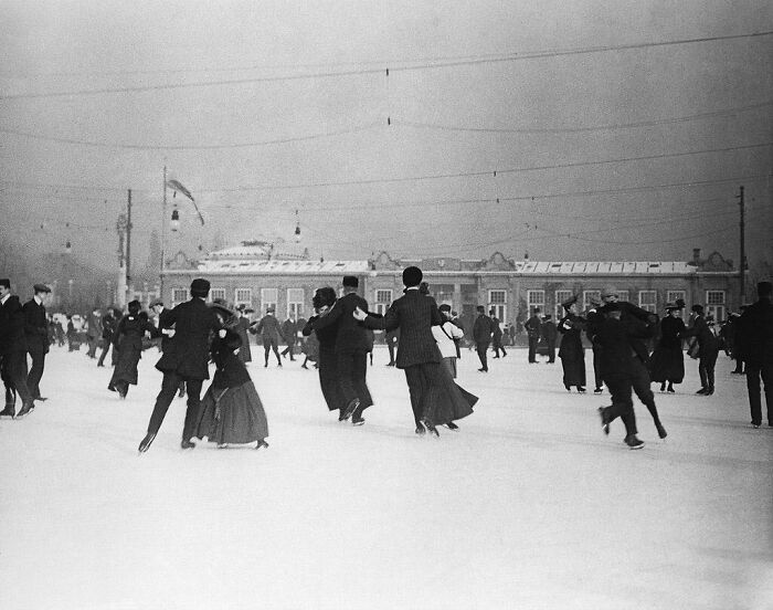 Personas patinando sobre hielo en una plaza en invierno, transportándote al pasado. Fotografías históricas evocadoras.