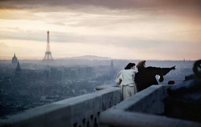 Pareja contemplando París al atardecer con la Torre Eiffel al fondo, evocando momentos históricos.